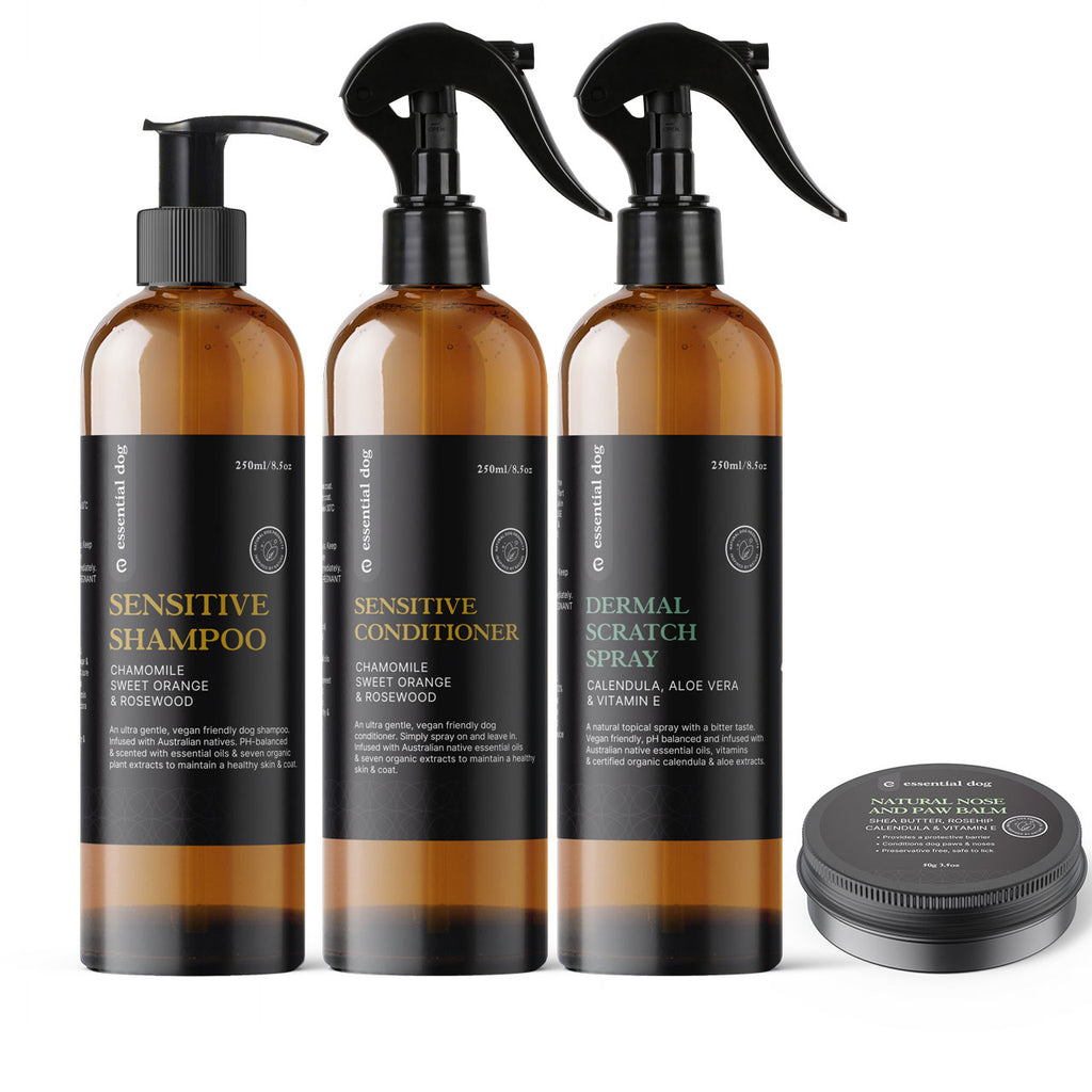 Set of three amber bottles labeled 'Sensitive Shampoo', 'Sensitive Conditioner', and 'Dermal Scratch Spray' with a small round container on a white background.